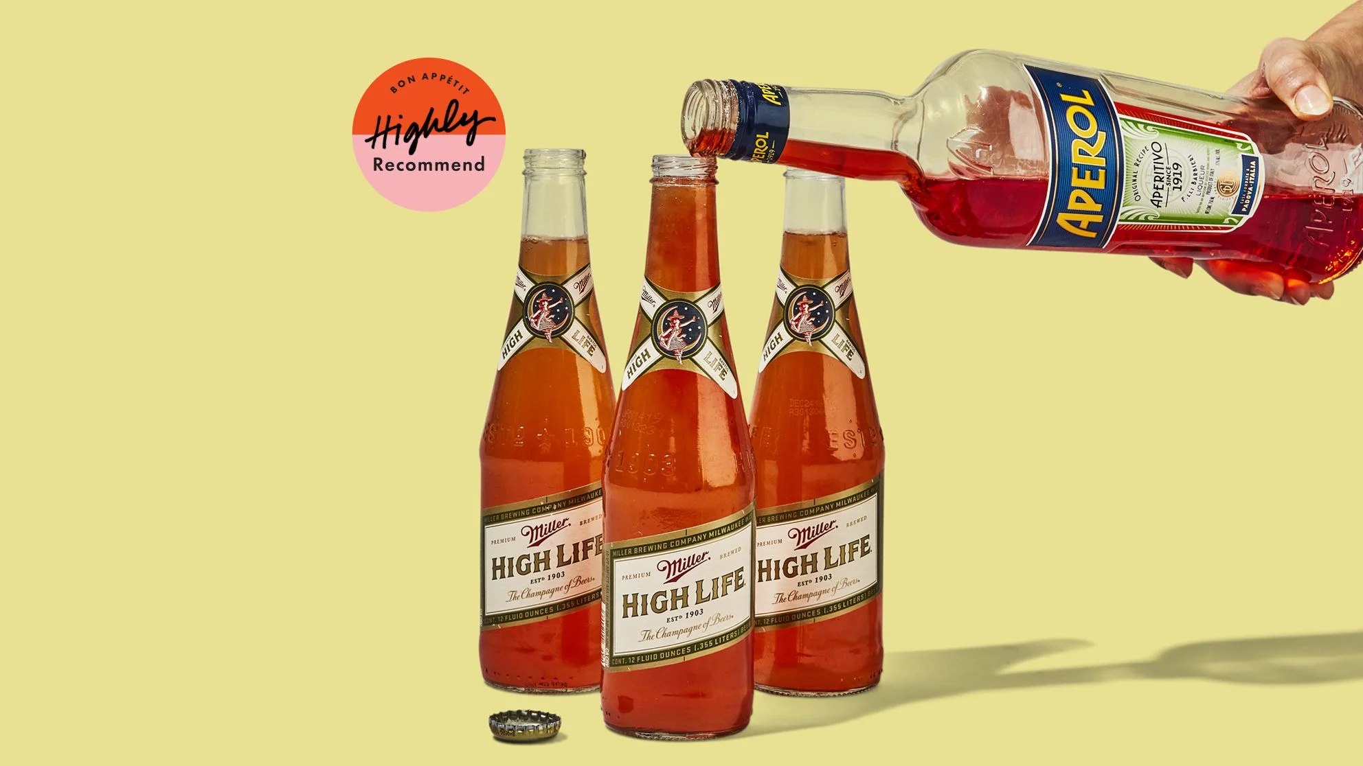 Aperol being poured into 3 bottles of Miller High Life for Spaghett cocktails.