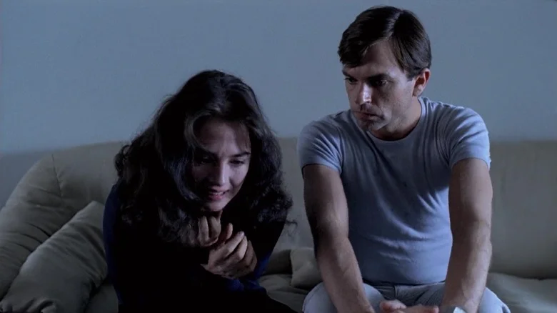 Sam Neill as Mark trails sits on the couch with Isabelle Adjani as Anna in Possession