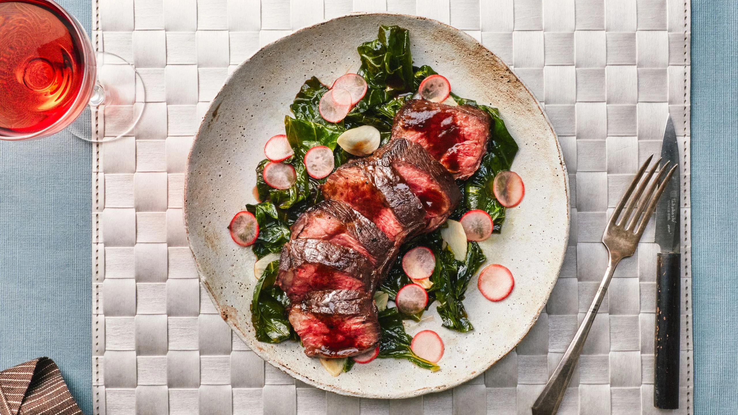 Chris Steak for one plated on a stone plate on a silver woven placemat.