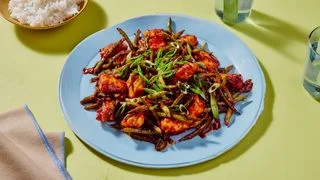 Gochujang Chicken and Scallion Stir Fry  on a blue plate and on a green background