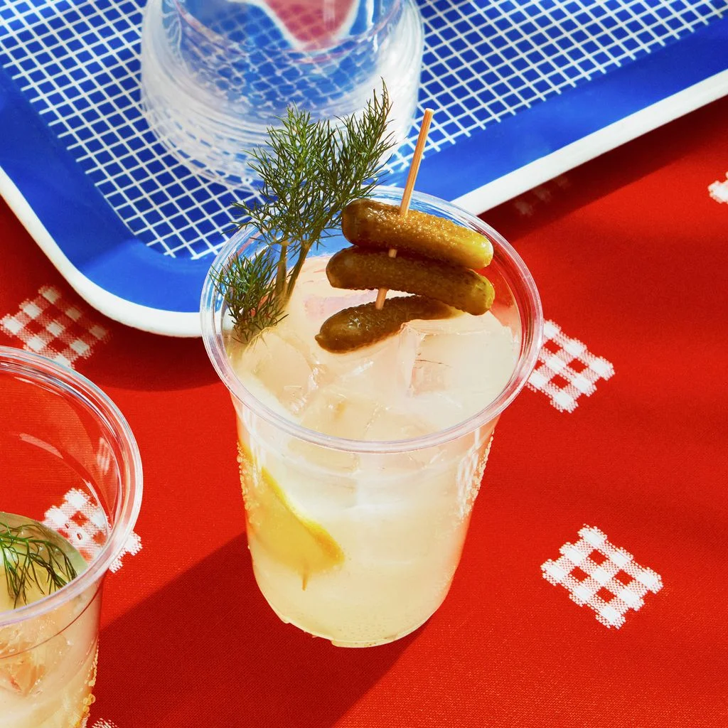Pickle brine water lemon juice and sugar mixed into a glass pitcher filled with ice and garnished with sprigs of dill...