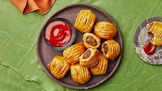 Plate of zucchini sausage rolls on green linen.