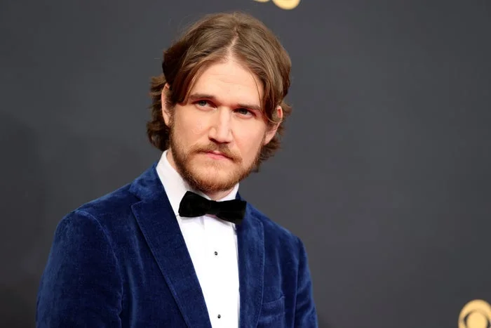 Man in a velvet suit and bow tie on a formal event red carpet, looking to the side