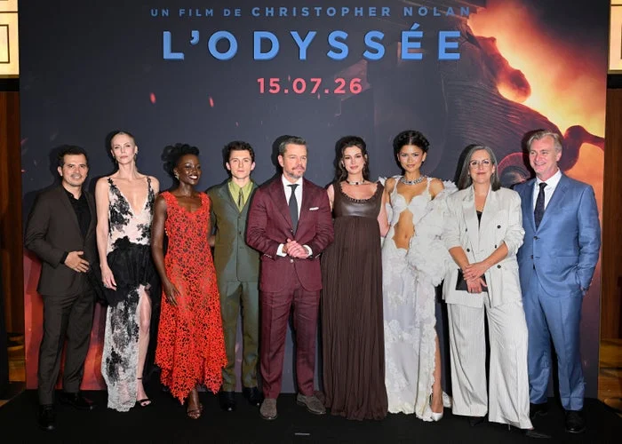 Cast of "L'Odyssée" on red carpet; diverse styles from formal suits to elegant gowns