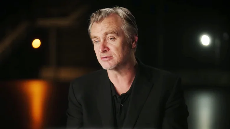 Christopher Nolan sits in a dark room during an interview behind the scenes of The Odyssey
