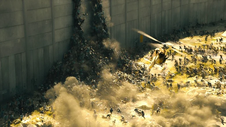 A horde of zombies pile up against a huge wall as a helicopter flies overhead in World War Z