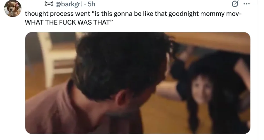 A person is startled as another person peeks out from under a table. Text above them expresses shock, referencing a movie scene