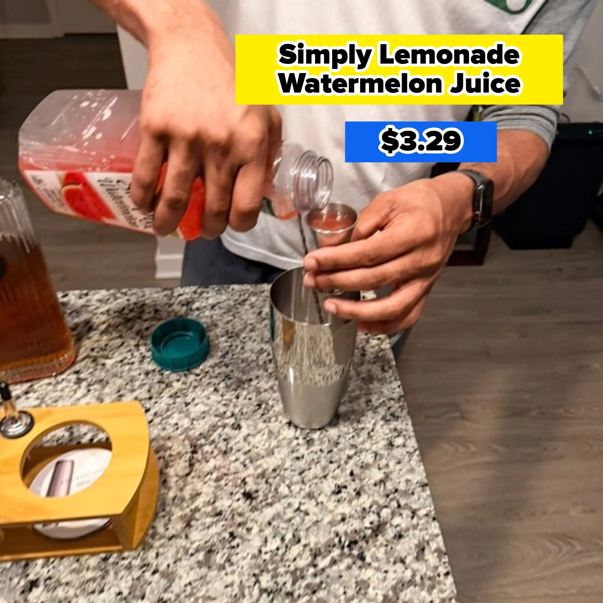 Person pouring juice into a cocktail shaker on a kitchen counter next to a bottle and a yellow utensil holder
