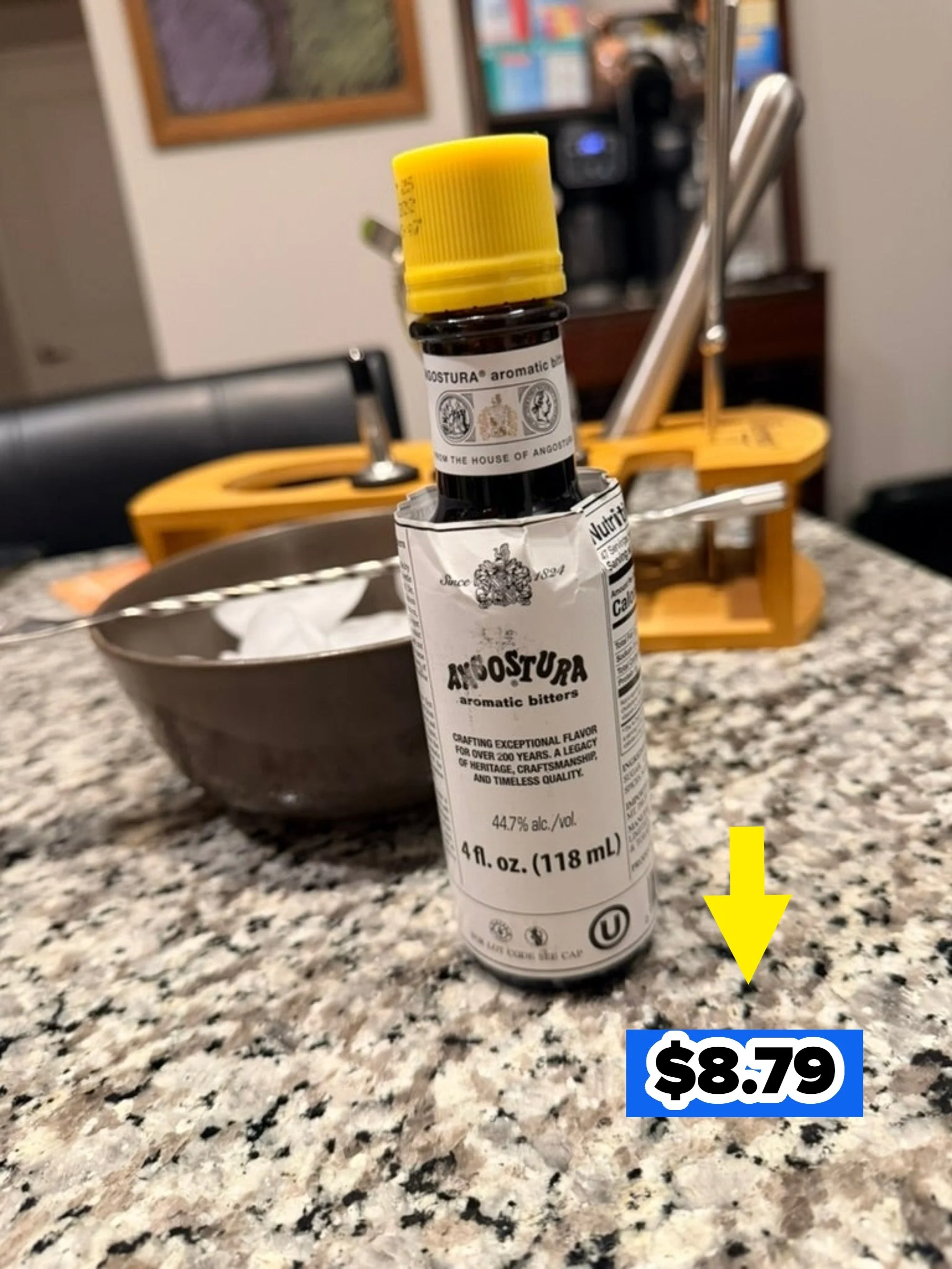 Bottle of Angostura aromatic bitters on a kitchen counter, beside a bowl and juicer in the background