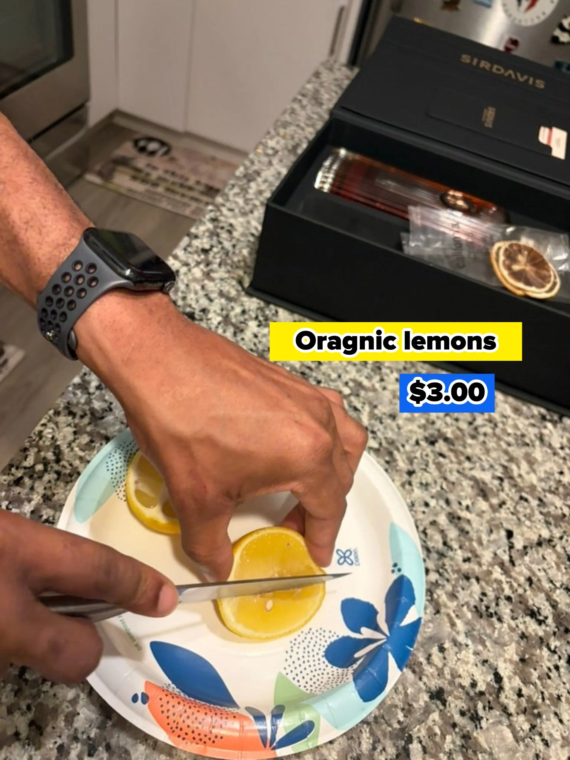 Person slicing lemons on a floral paper plate in a kitchen with a black box nearby