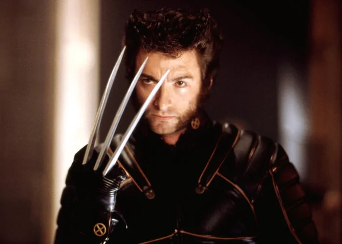 Man in superhero costume with metal claws extended, looking intense