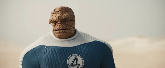 A character with a rocky exterior, wearing a blue suit with a number 4 emblem, stands in a desert landscape