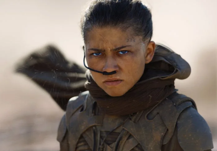 Zendaya in Dune: Part Three with intense expression in a sci-fi setting, wearing tactical gear with a nose device and scarf