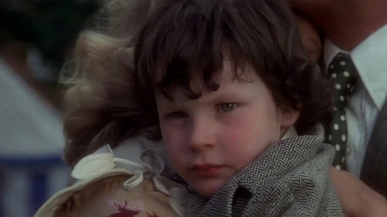 A close-up of Harvey Spencer Stephens as Damien in The Omen while being held.