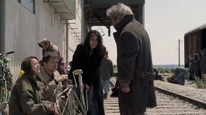 Anne Laurent and her family on a train track talking to a man in a coat in Time of the Wolf