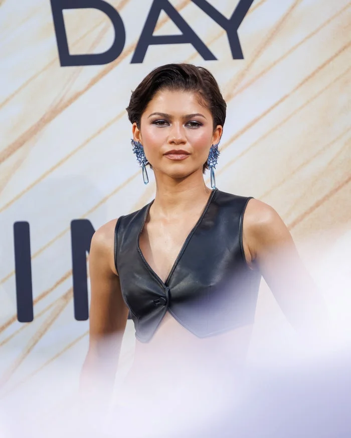 Zendaya in stylish leather top and statement earrings at a fashion event