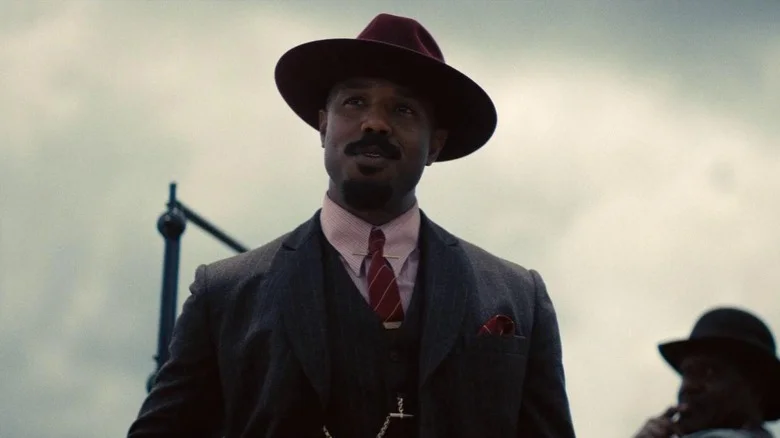 Michael B. Jordan as Smoke standing by the car in Sinners