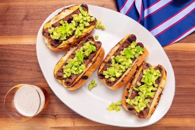 Bratwurst dressed on white platter placed on a wood surface