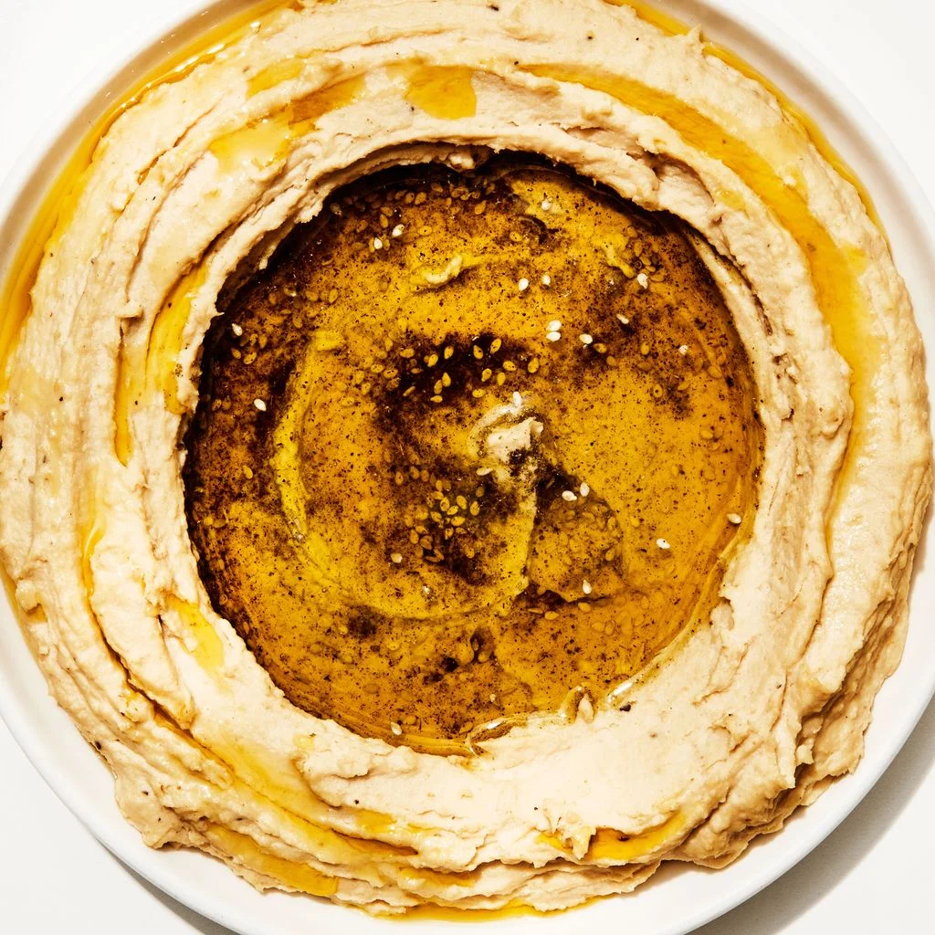 Overhead shot of hummus swooshed around the edge of a bowl with a garnish of olive oil and za'atar in the center.