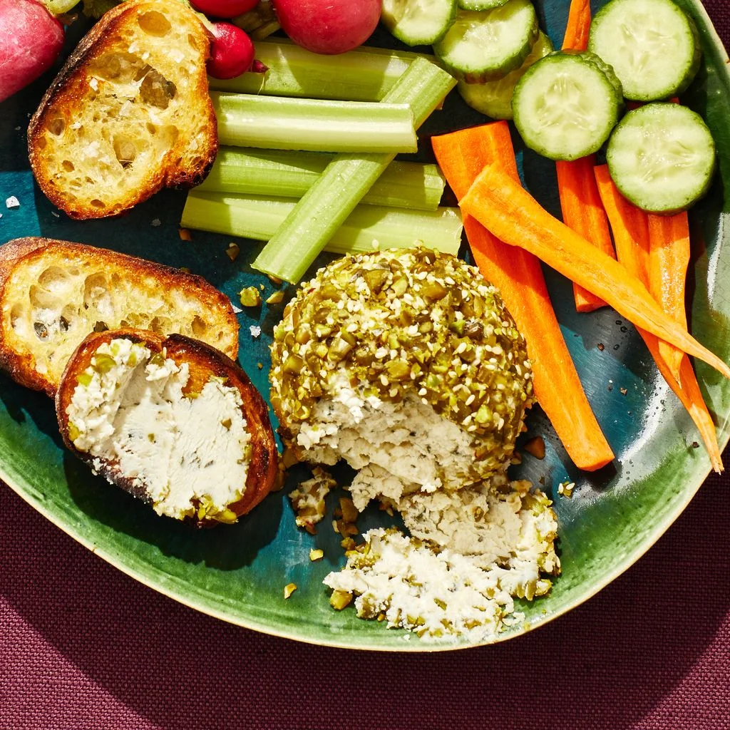 Pistachio cheeseball on plate with crudite and crostini.