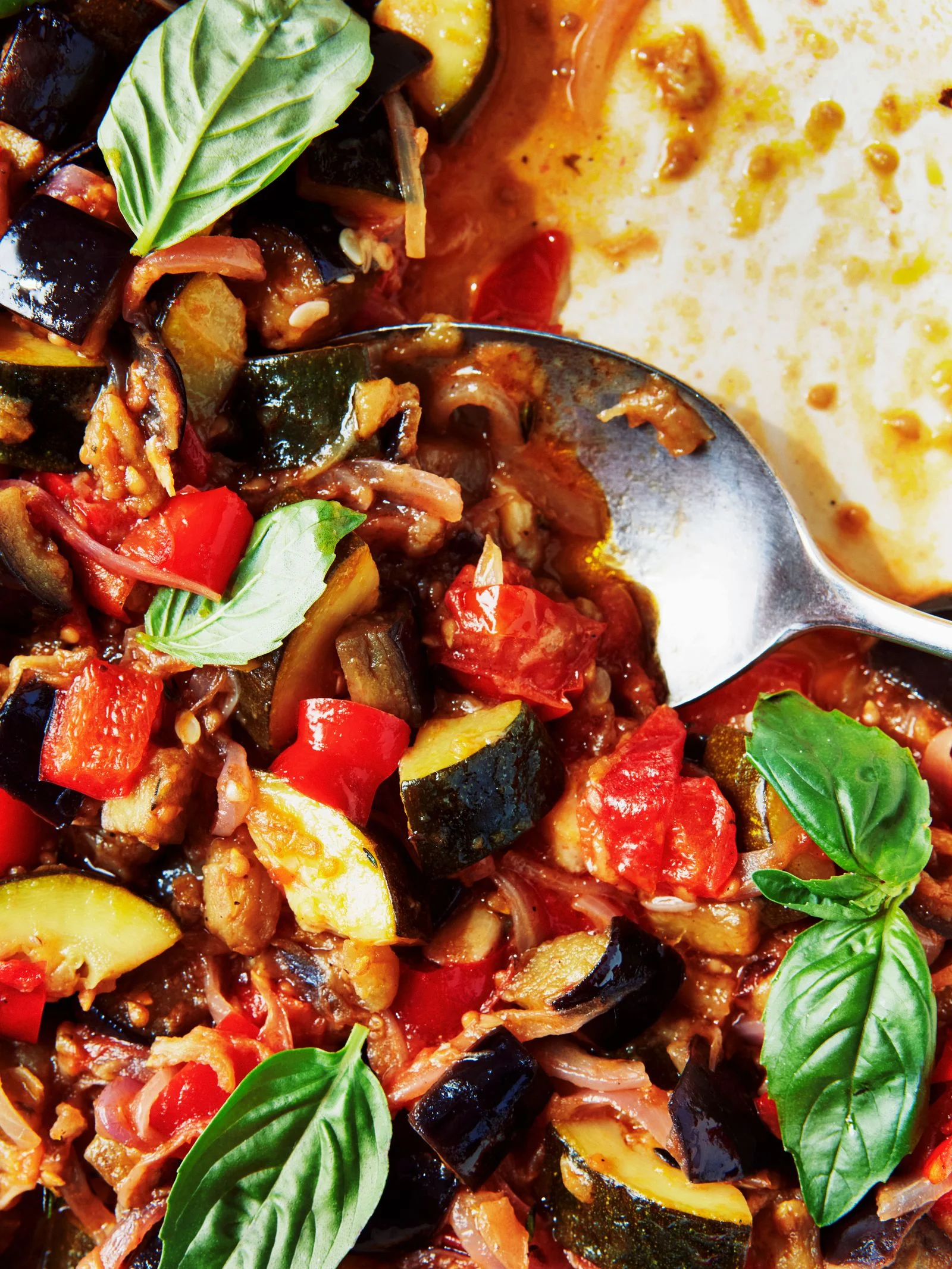 Closeup of French ratatouille with eggplant zucchini red onions cherry tomatoes and red bell pepper in a stew pot.