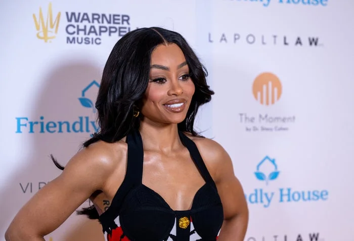 Blac Chyna in a stylish dress on a red carpet at a celebrity event, smiling for the camera