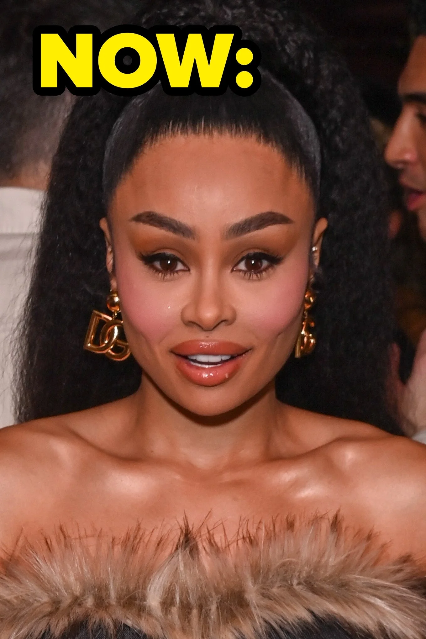 Blac Chyna posing at an event, wearing a strapless top with fur trim