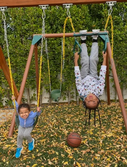 Dream Kardashian and King Cairo playing on a swing set