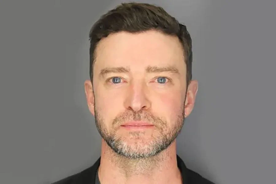 Justin Timberlake with short hair and facial stubble, dressed in a top, looks directly at the camera against a plain background