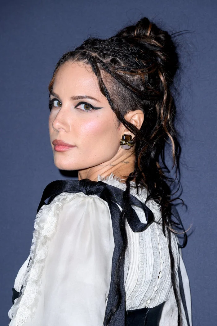 Halsey with braided hair and a textured updo, wearing a vintage-style blouse with ribbon accents, at an event