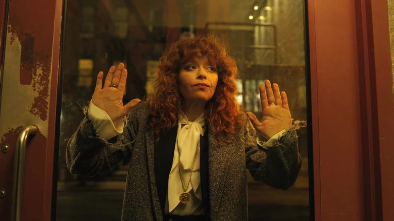Natasha Lyonne as Nadia Vulvokov holding her hands up a glass panel in a door in Russian Doll
