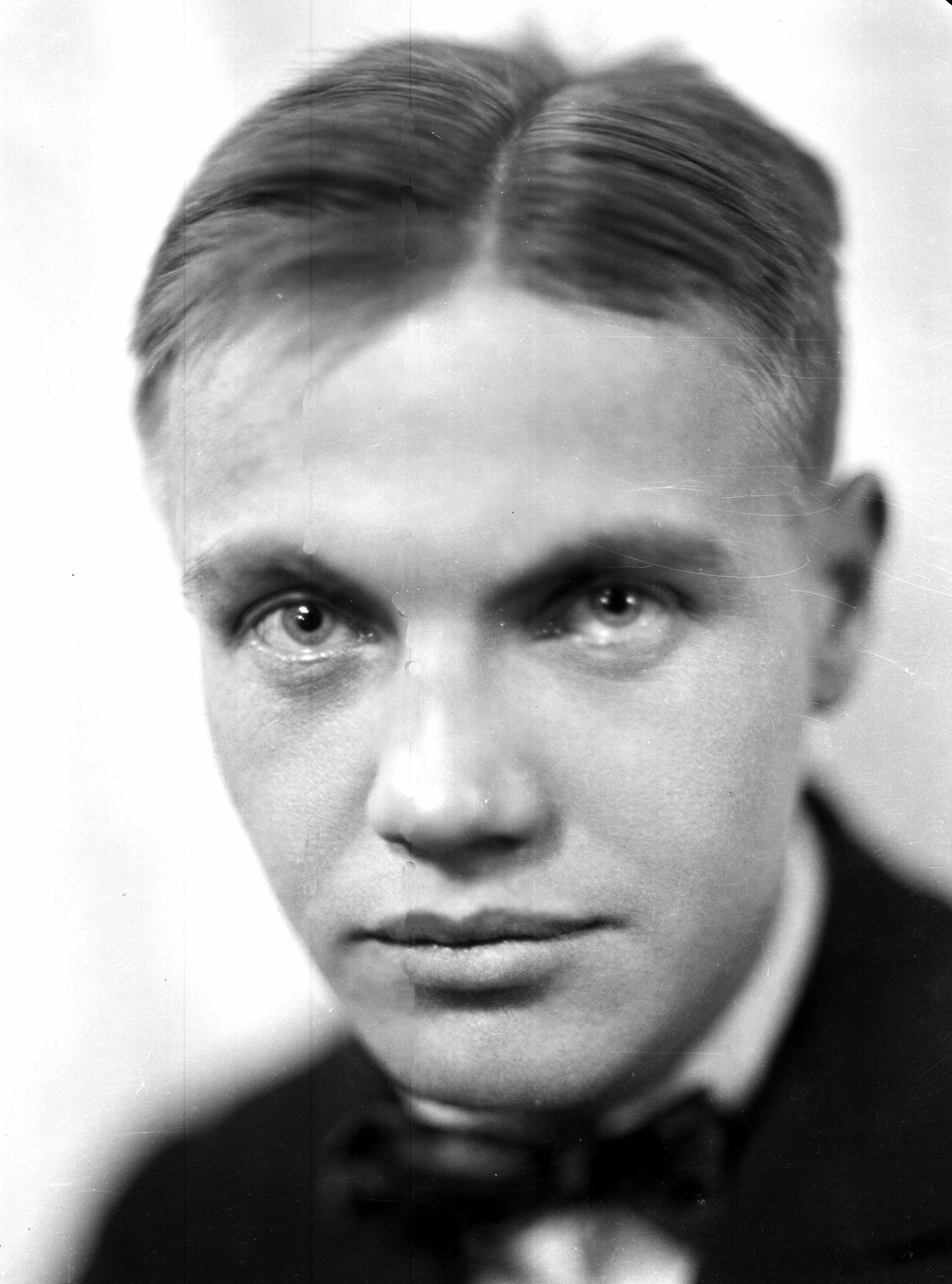 A portrait of a man, George Antheil,  with short, slicked-back hair and a bow tie, looking directly at the camera