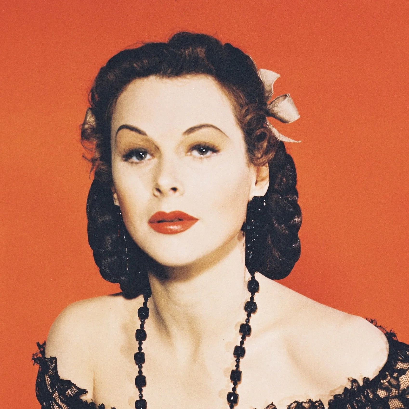 Hedy Lamarr in vintage attire with a lace-detailed off-shoulder dress and a beaded necklace. Hairstyle is classic, exuding a Hollywood glamour feel
