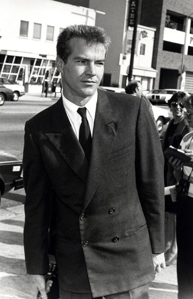 Man in retro double-breasted suit standing on a street, hands in pockets