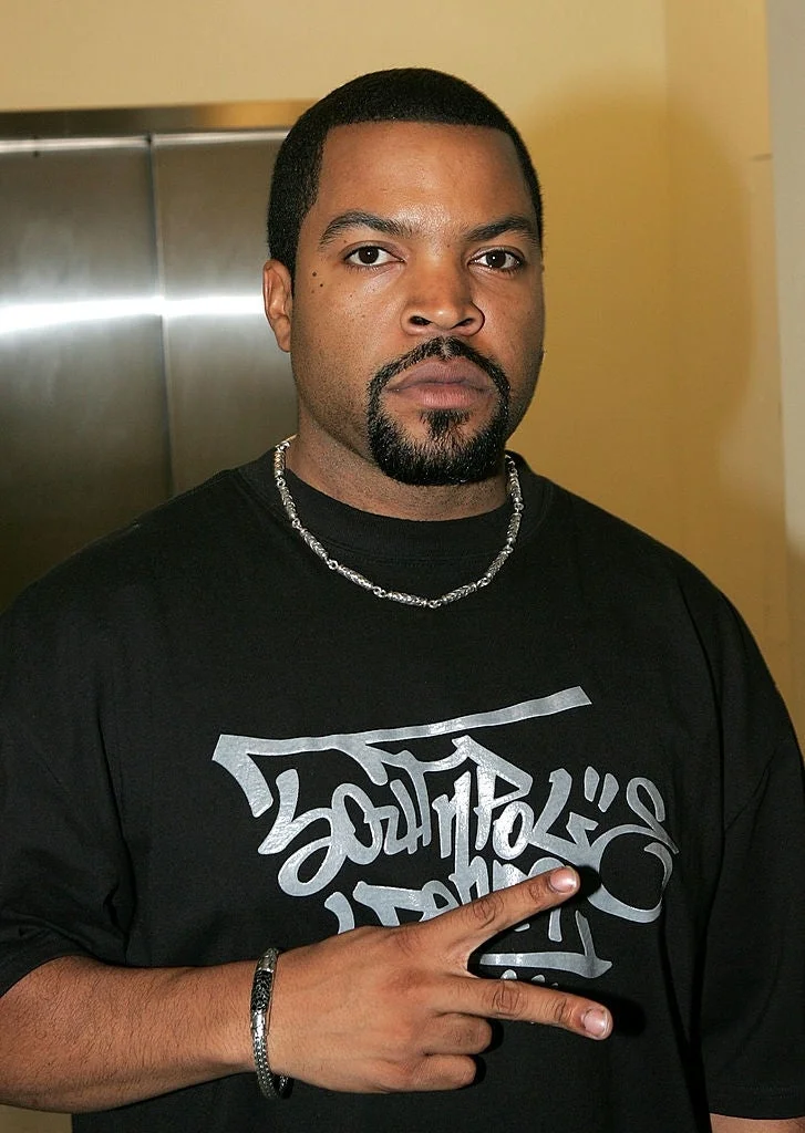 Person wearing a graphic black T-shirt and silver chain, making a peace sign with their hand