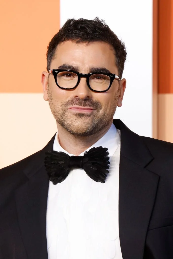 Person in formal attire with a bow tie and glasses at a celebrity event