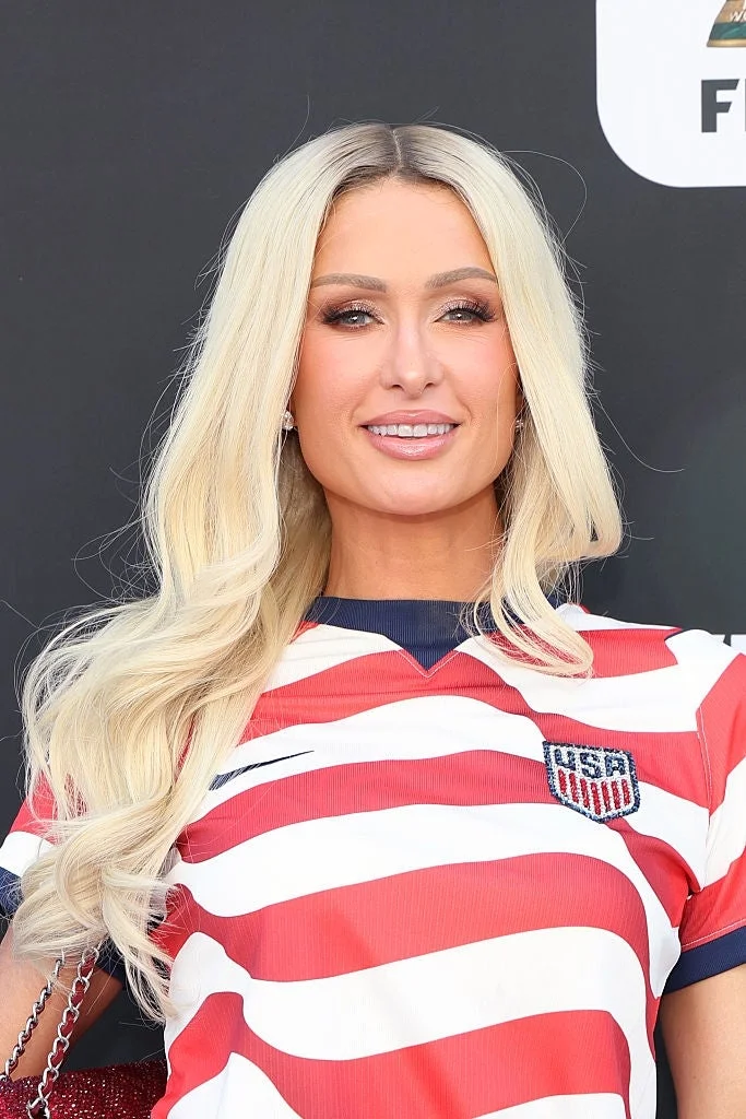 Person in a USA soccer jersey with long blonde hair, smiling at a public event
