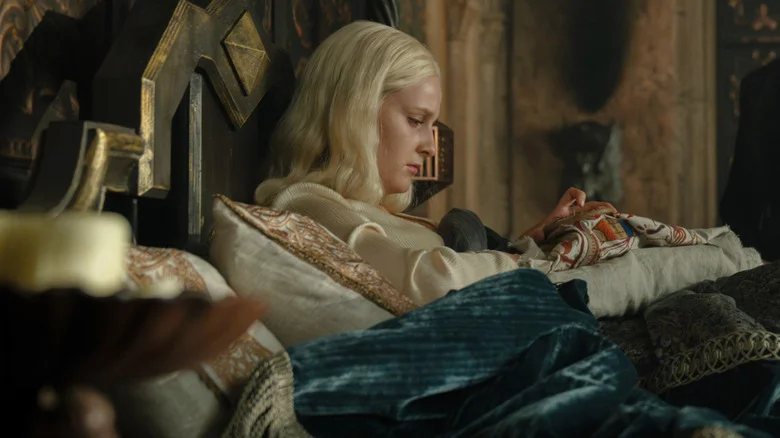 Helaena looking sad as she stitches in her bed in House of the Dragon