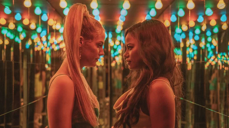 Stefani and Zola staring at each other in a room full of mirrors and lights in Zola