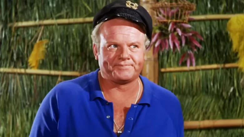 Alan Hale Jr.'s Captain Jonas Grumby looks annoyed as he stands in a shack in Gilligan's Island.jpg