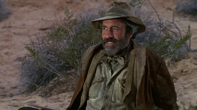 Cable Hogue (Jason Robards) sits smiling in a desert in The Ballad of Cable Hogue