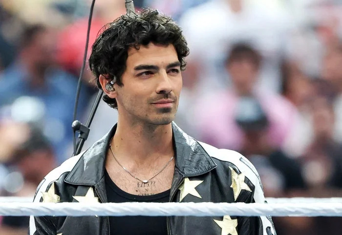 Person wearing a star-patterned jacket and earpiece, standing in a public setting