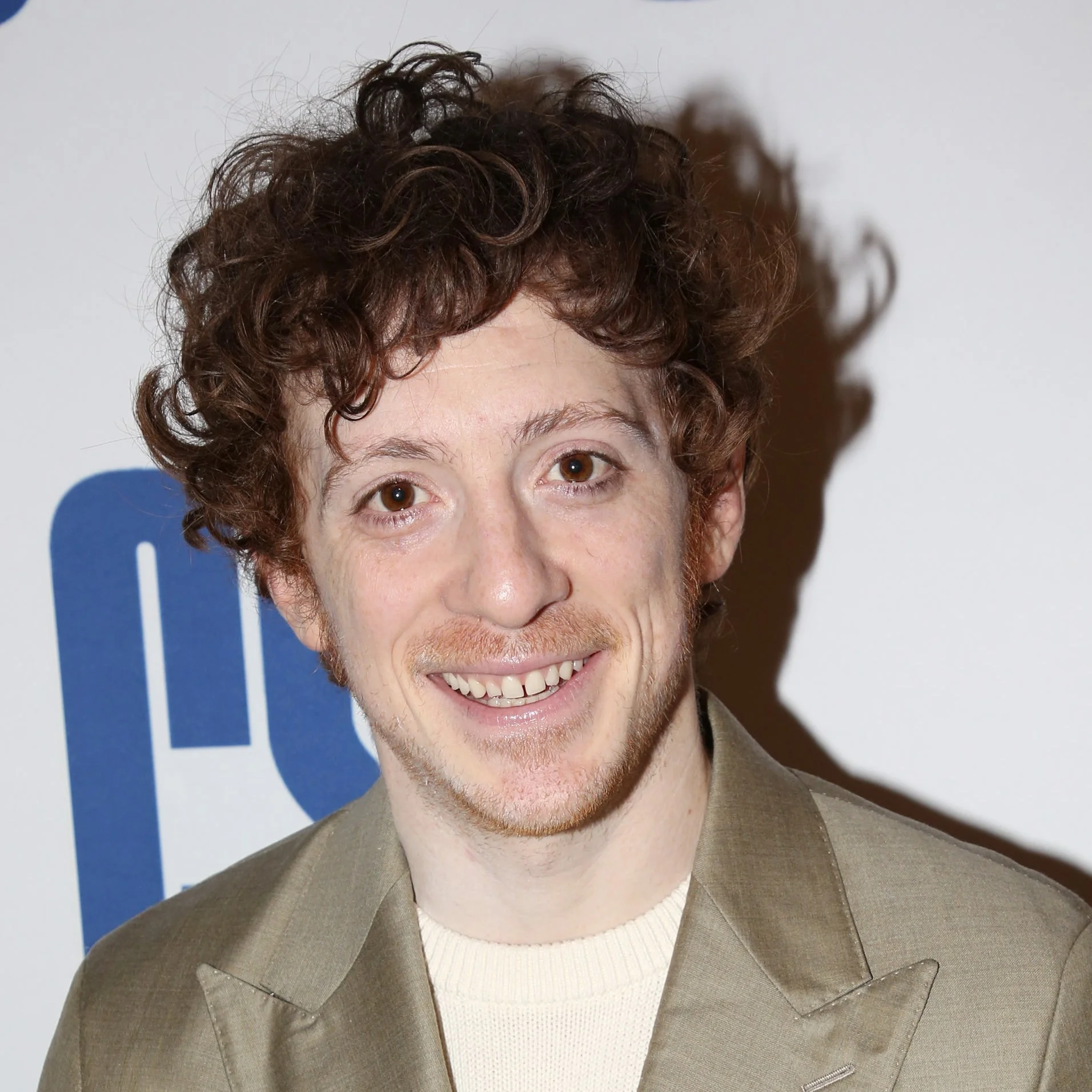 Person in a light suit smiling at an event