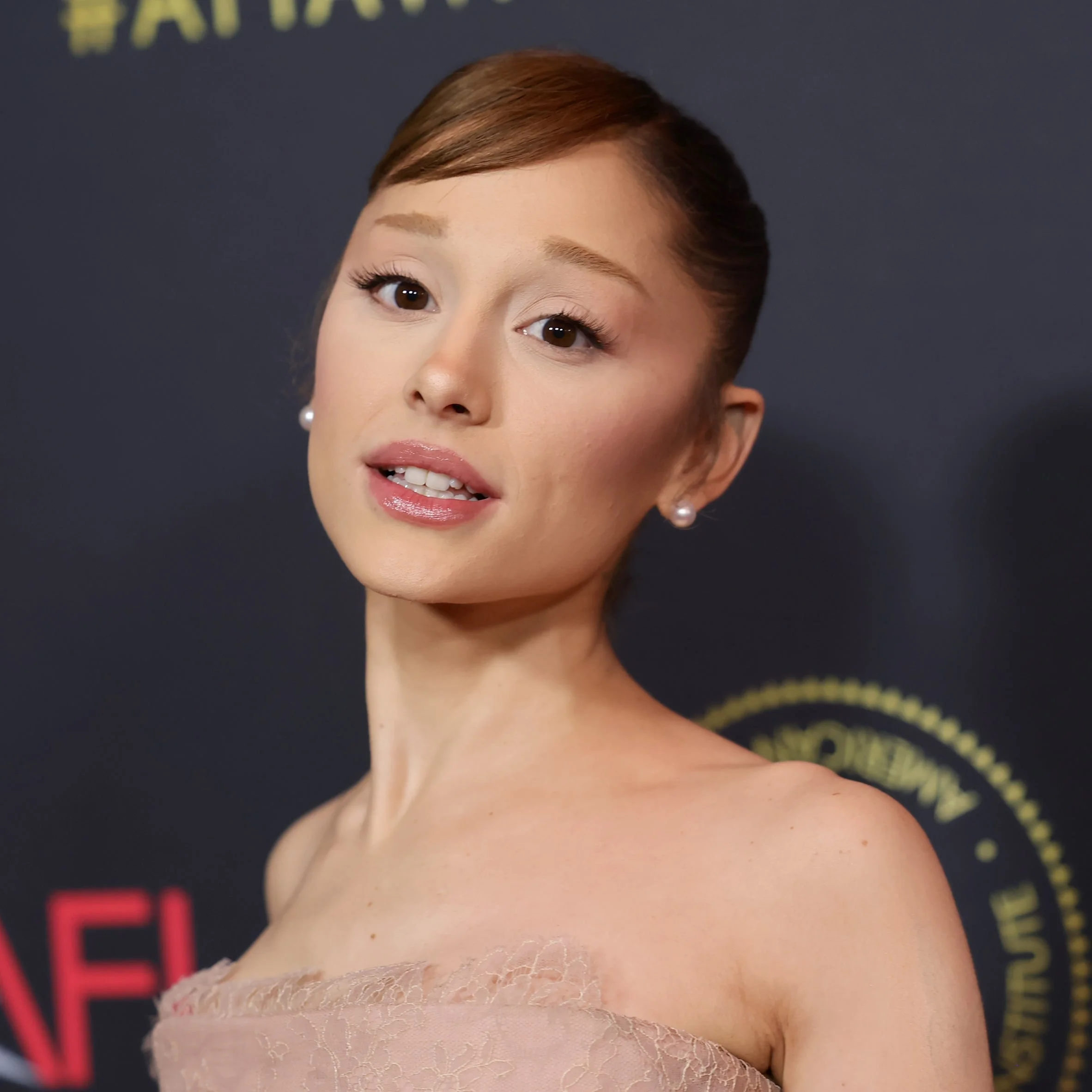 Celebrity on the red carpet wearing an elegant, strapless dress, with hair styled in an updo