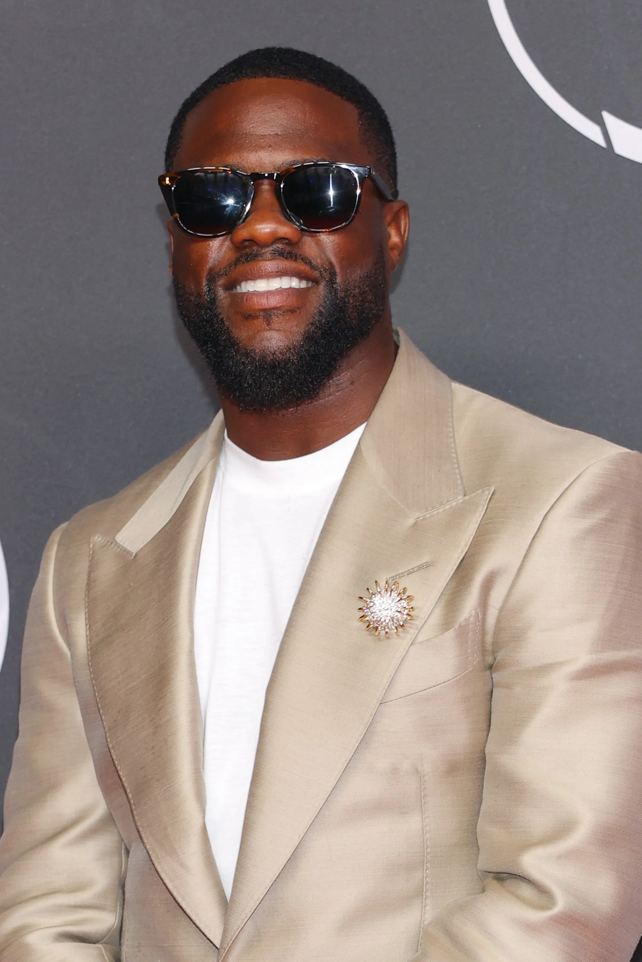 Person in sunglasses wearing a stylish suit and white shirt, smiling on the ESPYS red carpet