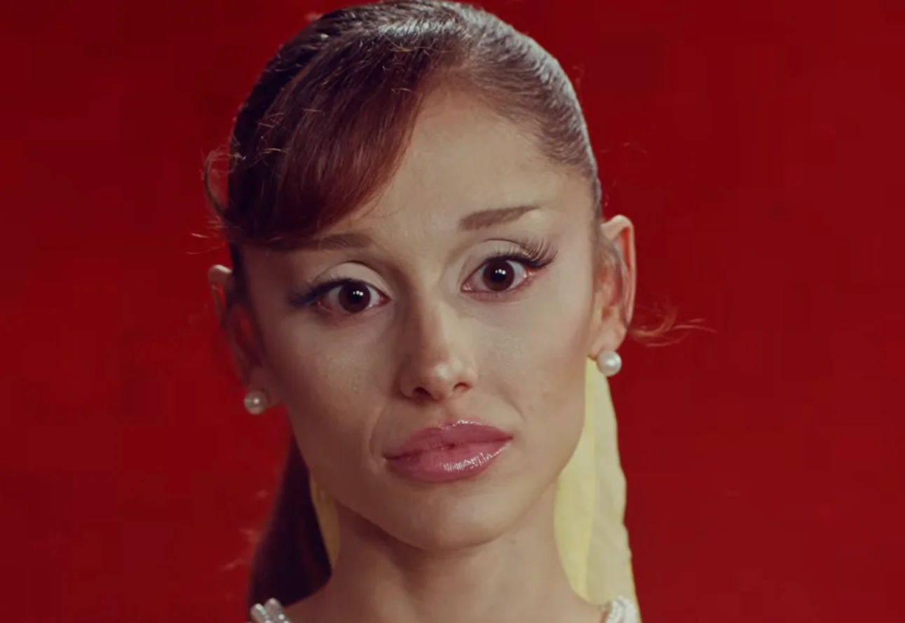 Woman with pearl necklace and earrings against a red background, styled with an updo and elegant attire