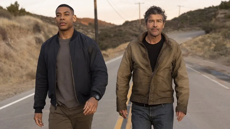 Kyle Chandler as Hal Jordan walking next to Aaron Pierre as John Stewart on a dusty road in Lanterns