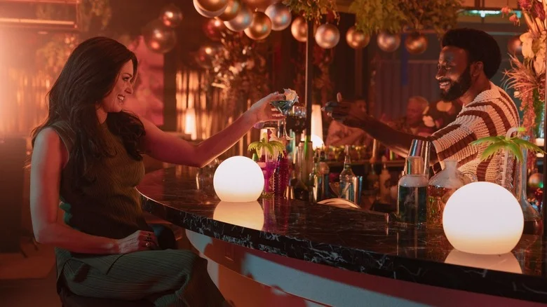 Commander Chin-Riley being handed a drink across a bar by Dr. M'Benga on Star Trek: Strange New Worlds