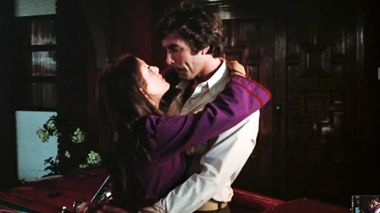 Tom Selleck's James Robertson holds Barra Grant's Chris Robertson as they stand next to a car in Daughters of Satan