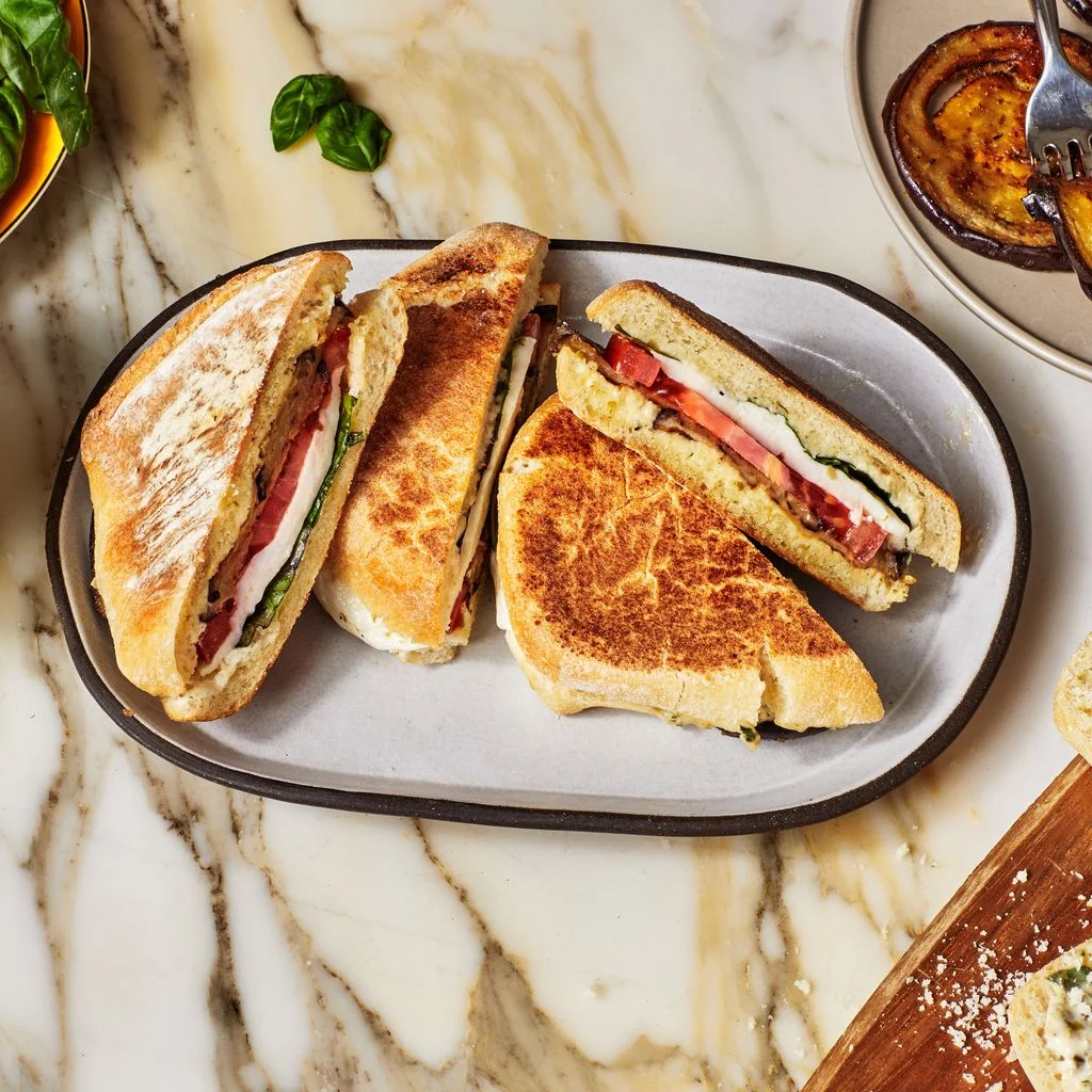 Panini Alla Norma on a white plate on a marble surface